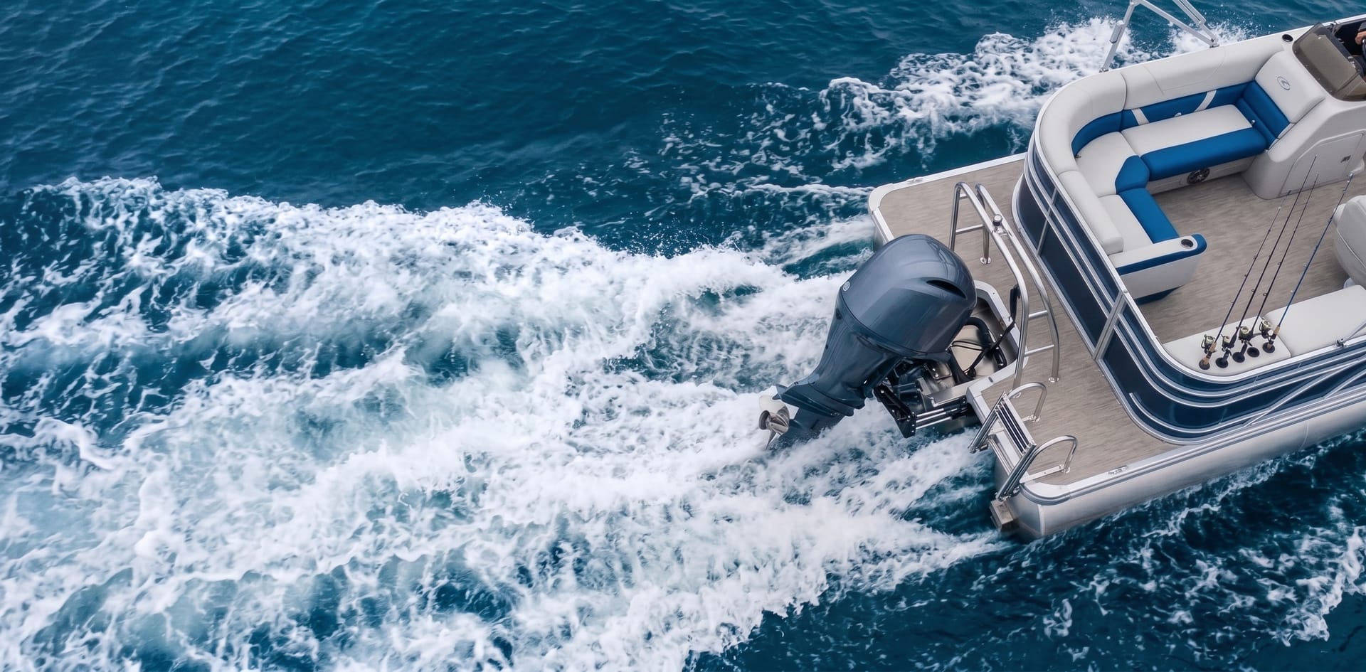 Pontoon boat cruising with an outboard trolling motor churning a wake